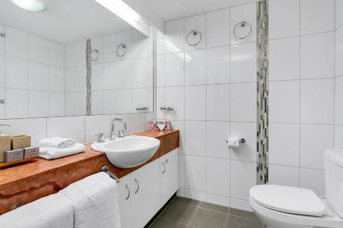 a white bathroom with a sink and a toilet at Cairns Esplanade Apartment in Cairns