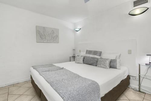 a white bedroom with a large white bed with pillows at Cairns Esplanade Apartment in Cairns