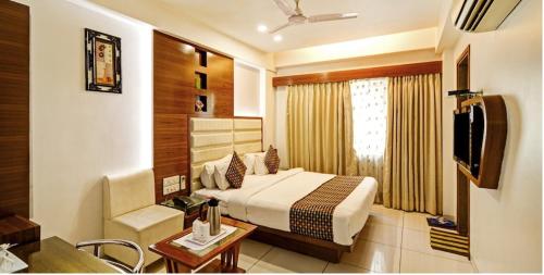 a bedroom with a bed and a desk and a television at Atithi The Hotel in Ahmedabad