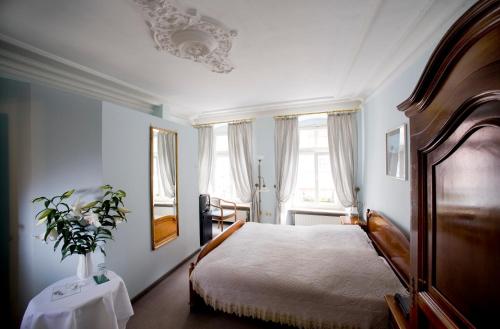 Hotel Goldener Hecht في هايدلبرغ: غرفة نوم بسرير و إناء من الزهور