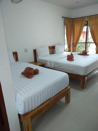 two beds in a room with towels on them at Lanta Cottage - SHA Plus in Ko Lanta
