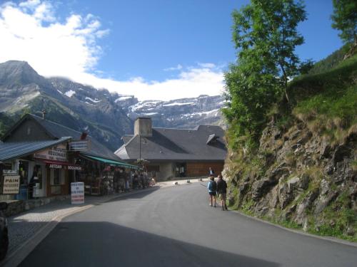 two people walking down a street next to a mountain at Chambres d'hôtes L'Astazou in Gavarnie