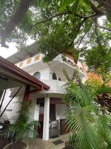 a white house with trees in front of it at Una Beach Hotel & OLU Cafe in Unawatuna
