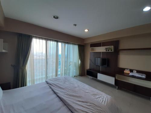 Cozy Tamansari Hive Cawang by Bonzela Property في جاكرتا: غرفة نوم بسرير كبير ونافذة كبيرة