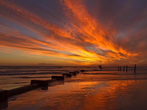 a sunset on a beach with the ocean at Ocean-Song in Strand