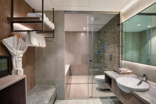 a bathroom with a shower and a sink and a toilet at Amoravida By 7 Apple Resorts, Goa in Mandrem