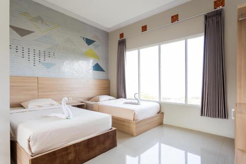 a bedroom with two beds and a large window at Villa Panderman Indah in Batu