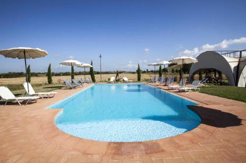 una grande piscina con sedie e ombrelloni di Relais La Leopolda a Cortona
