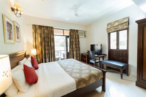 a bedroom with a bed and a desk and a window at Neelam's The Grand Hotel Goa in Calangute