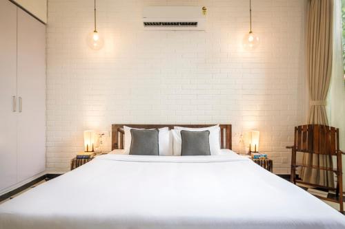 a bedroom with a large white bed with pillows at La Zamora, 3BHK Villas near Vagator & Anjuna Beach, North Goa with Private Pool, Garden, Terrace & Security in Assagao