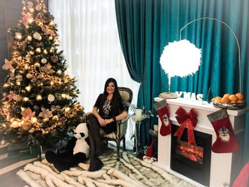 a woman sitting in a chair next to a christmas tree at Pleiada Boutique Hotel & Spa in Iaşi