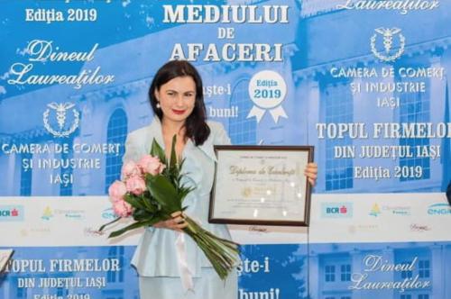 a woman holding a certificate and a bouquet of flowers at Pleiada Boutique Hotel & Spa in Iaşi