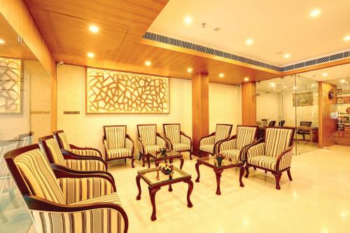 a waiting area with chairs and tables in a lobby at Hotel Floral Park in Kottayam