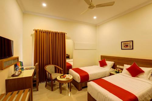 a hotel room with two beds and a television at Hotel Floral Park in Kottayam