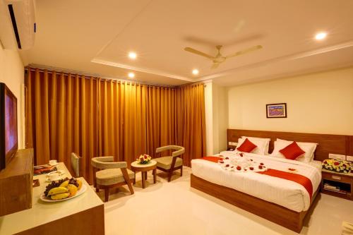 Habitación de hotel con cama, mesa y sillas en Hotel Floral Park en Kottayam