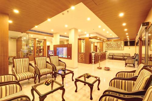 a lobby with chairs and tables and a television at Hotel Floral Park in Kottayam