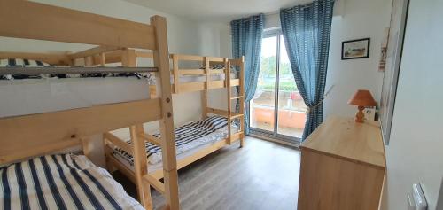 a bedroom with two bunk beds and a balcony at Appartement vue sur mer et port in Grandcamp-Maisy