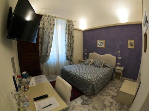 um pequeno quarto com uma cama, uma mesa e uma secretária em Five Roses Bed & Breakfast em Pisa