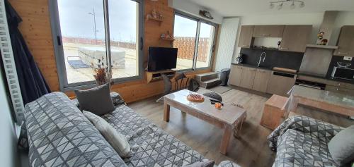 a living room with a couch and a table at Appartement vue sur mer et port in Grandcamp-Maisy