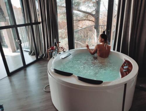 a woman sitting in a bath tub in a room at Exclusive Jacuzzi Apartaments Klaipėda in Aukštkiemiai