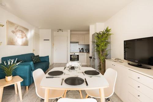 - un salon avec une table blanche et un canapé bleu dans l'établissement Port-Fréjus, LE PALADIEN, appartement 2 pièces climatisé, terrasse & parking, à Fréjus