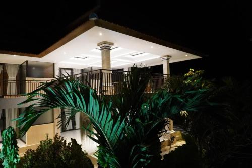 a house with a palm tree in front of it at Umah Dayuh in Uluwatu