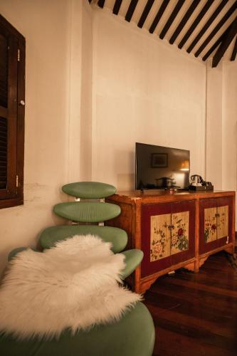 a room with two green chairs and a television at Hotel Penaga in George Town