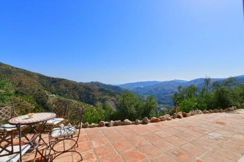 a patio with tables and chairs and mountains in the background at Casa Afrodite in Almuñécar