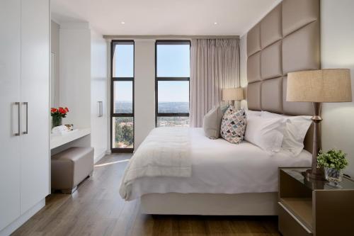 sypialnia z dużym łóżkiem i dużymi oknami w obiekcie Masingita Towers Executive Suite w mieście Johannesburg