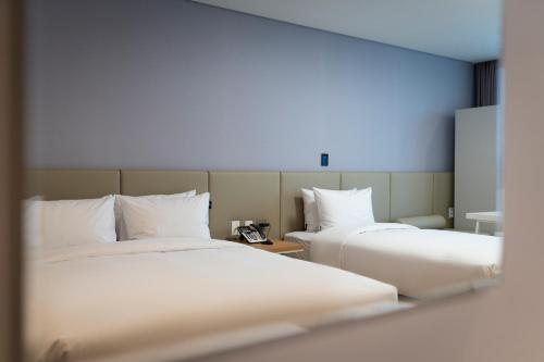 a hotel room with two beds and a mirror at Best Western Asan Hotel in Asan