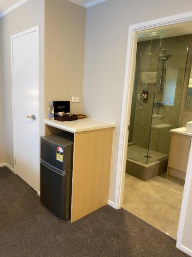 a bathroom with a shower and a counter with a refrigerator at Takapuna International Motor Lodge in Auckland