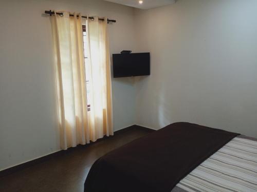 - une chambre avec un lit et une télévision murale dans l'établissement Wayanad Cocos Villa, à Tariyod