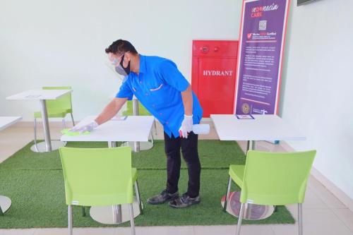 a man standing next to a table with chairs at Cordex Hotel Ancol in Jakarta