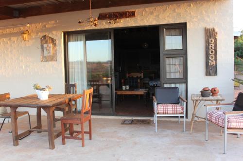 a wooden table and chairs on a patio at PurePlaas Self catering Volmoed Oudtshoorn Klein Karoo in Oudtshoorn