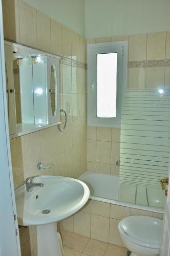 a bathroom with a sink and a tub and a toilet at Seafront Villa Kefaloniaprivatevillas in Trapezaki