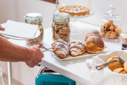 a person is serving food on a table with pastries at B&B Giardinello in Comiso