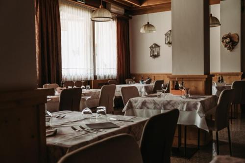 una sala da pranzo con tavoli e sedie in una stanza con di Hotel Primiero a Fiera di Primiero