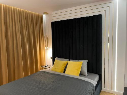 a bedroom with a bed with two yellow pillows at Apartamenty Manhattan in Legnica