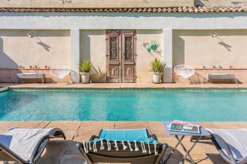 - une piscine avec des chaises et une porte dans l'établissement Hôtel La Suite, à Villeneuve-lès-Avignon