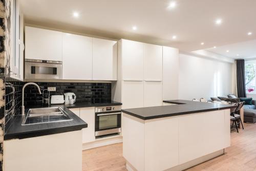 une cuisine avec des armoires blanches et un comptoir noir dans l'établissement Spacious apartment-2BR-4P-Boulevard Saint-Germain, à Paris