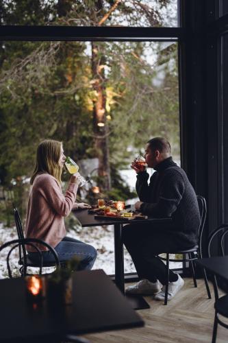 a man and woman sitting at a table eating food at Magical Pond Nature Igloos in Ruka