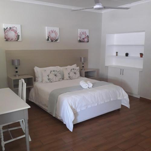 1 dormitorio con 1 cama con sábanas y almohadas blancas en Aflica Apartments, en Gaborone