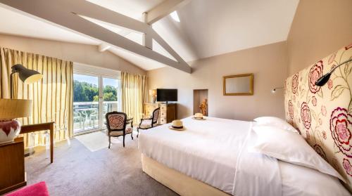 um quarto com uma grande cama branca e uma janela em Relais & Châteaux Hôtel La Réserve em Albi