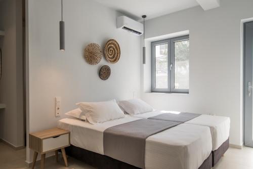 a white bedroom with a large bed and a window at Rivière Residence Paros in Naousa