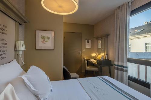 a hotel room with a bed and a desk and a window at Hôtel Littéraire Gustave Flaubert, BW Signature Collection in Rouen