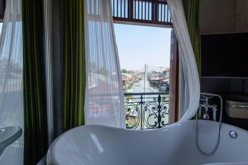 ein Bad mit einer Badewanne und ein Fenster mit Aussicht in der Unterkunft RoomQuest Rimrabeang at Amphawa in Amphawa