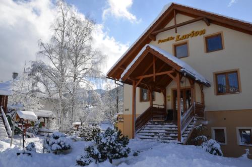 a building with snow on the ground in front of it at Penzion Larion in Kráľová Lehota