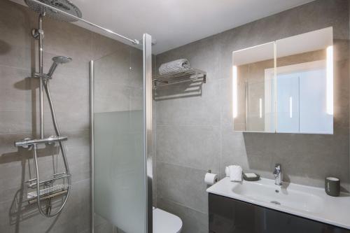 Un baño con ducha, lavabo y espejo. en Alondra, en Jávea