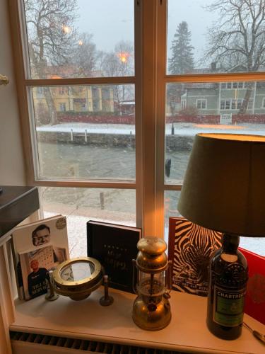 a table with a lamp and a clock and a window at Två Små Svin BnB in Trosa