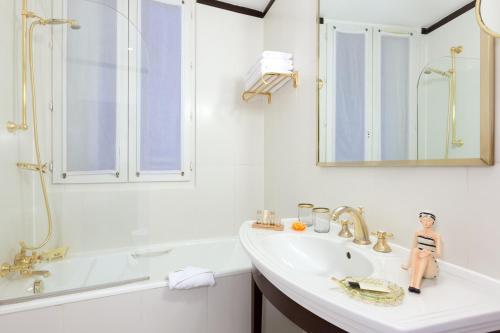 a bathroom with a sink, mirror and bathtub at Hôtel Waldorf Trocadéro Tour Eiffel in Paris